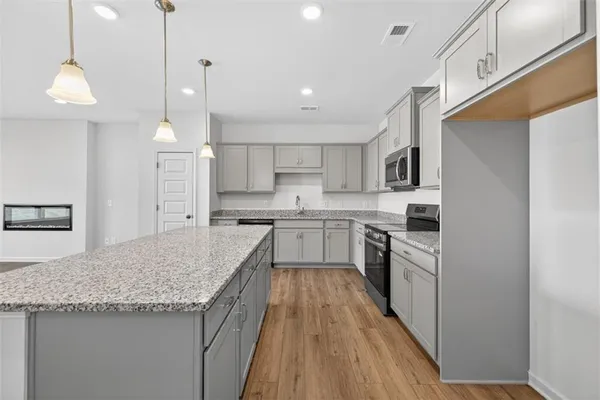 a kitchen with stainless steel appliances granite countertop a sink a stove a refrigerator and island with wooden floor