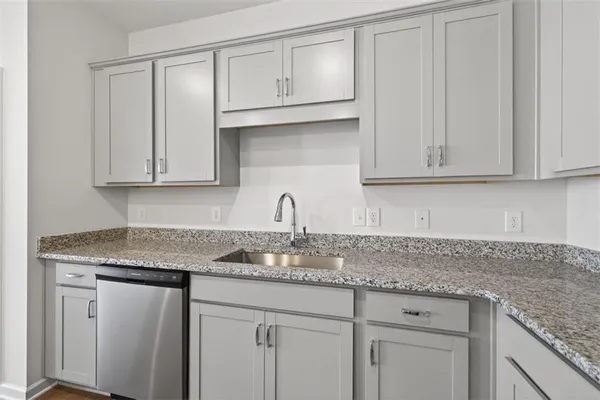 a kitchen with granite countertop white cabinets and a sink