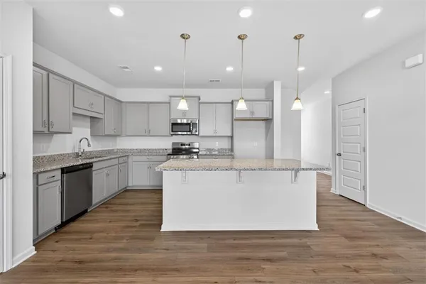 a large white kitchen with kitchen island a sink a stove a refrigerator and white cabinets