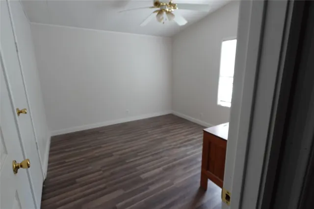 en empty room with wooden floor and fan