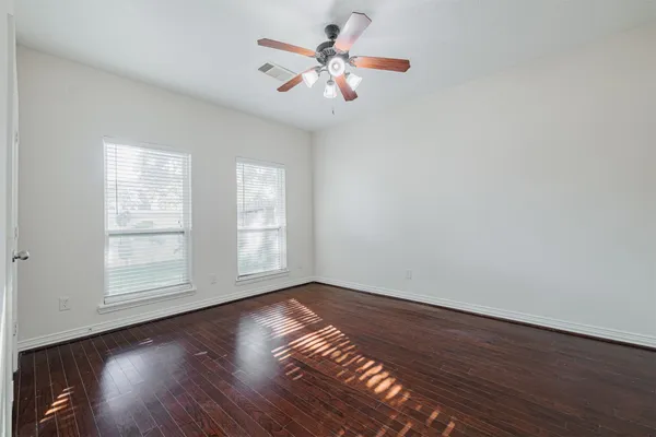 a view of an empty room with wooden floor fireplace and a window