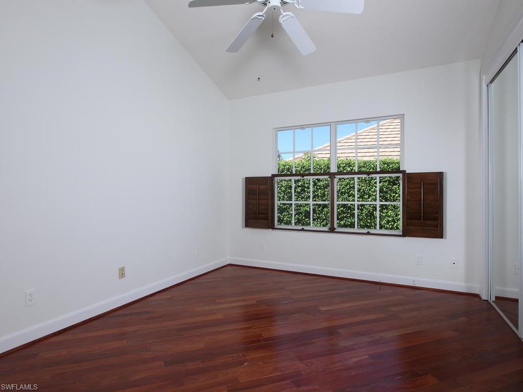 720 Turkey Oak Lane Naples, FL 34108 - Photo 11 of 17 an empty room with wooden floor and windows