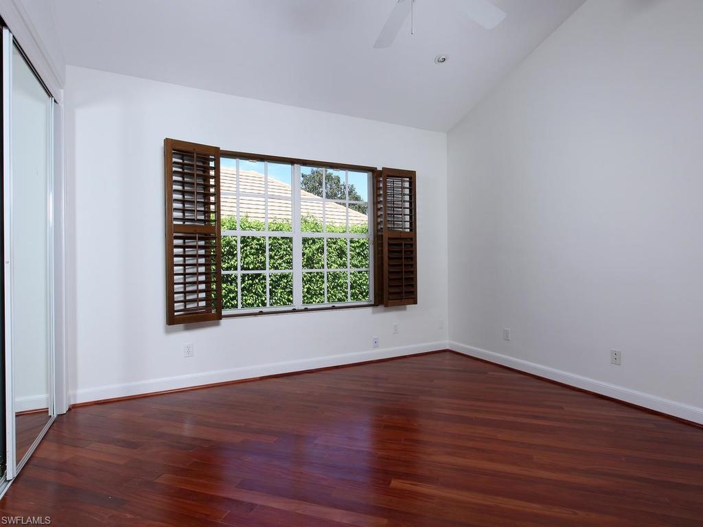 720 Turkey Oak Lane Naples, FL 34108 - Photo 13 of 17 a view of an empty room with wooden floor and a window