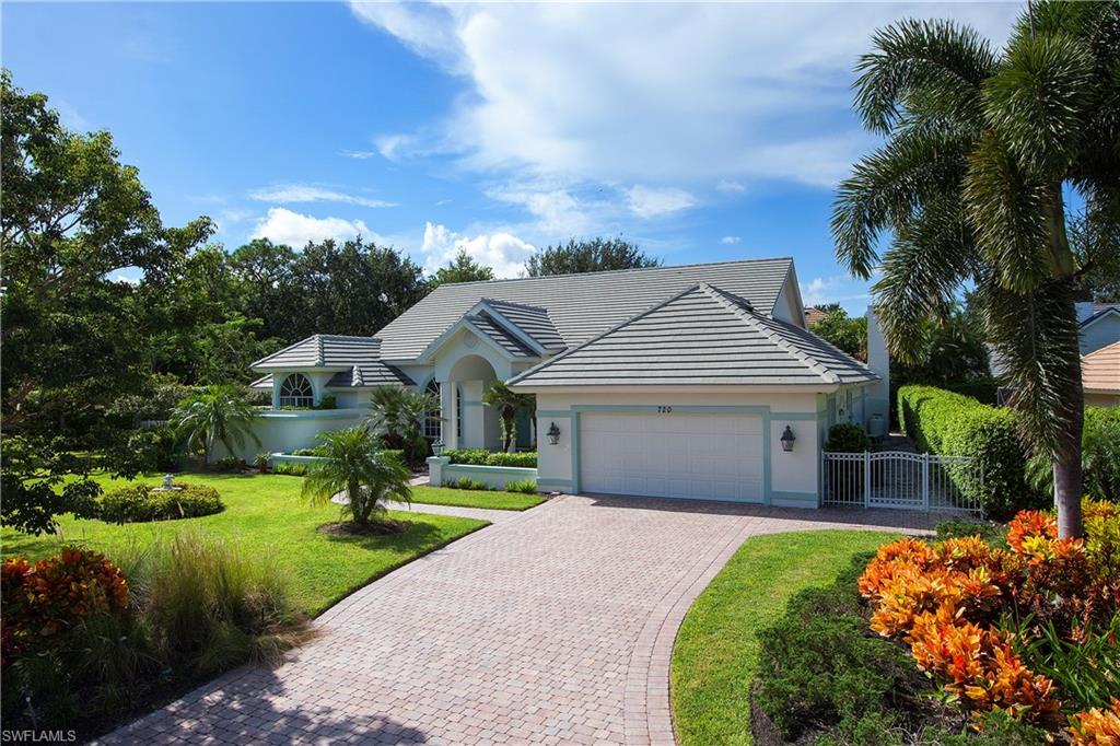 720 Turkey Oak Lane Naples, FL 34108 - Photo 2 of 17 a front view of a house with a garden and plants