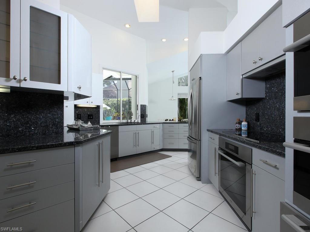 720 Turkey Oak Lane Naples, FL 34108 - Photo 7 of 17 a kitchen with stainless steel appliances granite countertop a sink a stove and a refrigerator