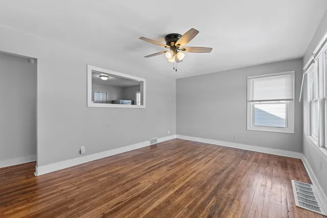 a view of empty room with wooden floor and fan