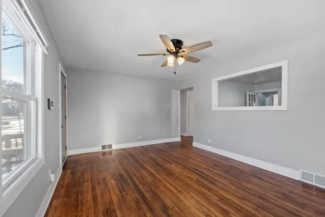 a view of empty room with wooden floor and fan