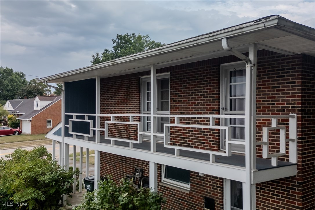 View of side of home featuring brick siding and a balcony