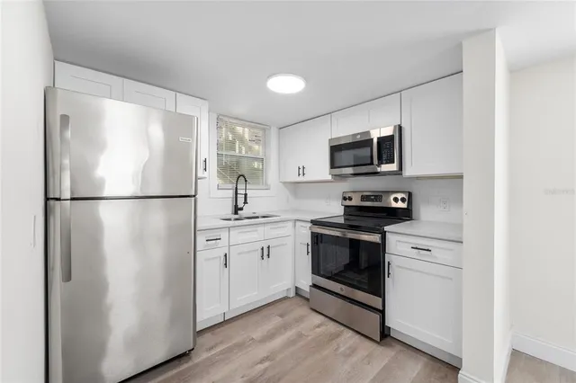 a kitchen with stainless steel appliances granite countertop a refrigerator a stove a sink and a microwave