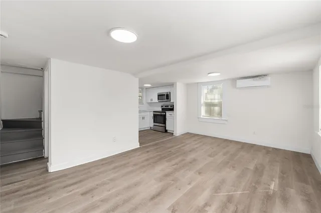 a view of an empty room with window and wooden floor
