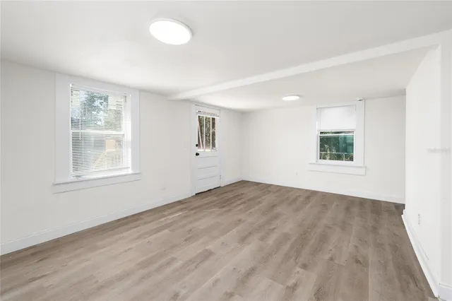 a view of an empty room with wooden floor and a window