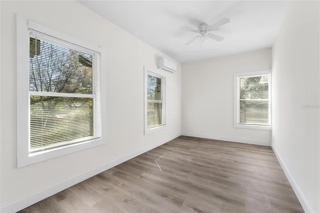 a view of an empty room with a window and wooden floor
