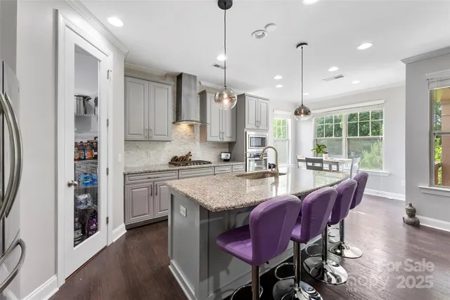 an open kitchen with granite countertop a stove a sink a dining table and chairs