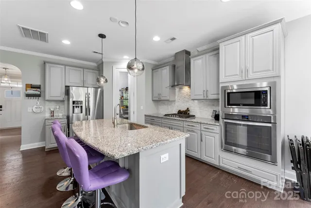 a kitchen with stainless steel appliances granite countertop a kitchen island hardwood floor sink stove dining table and chairs