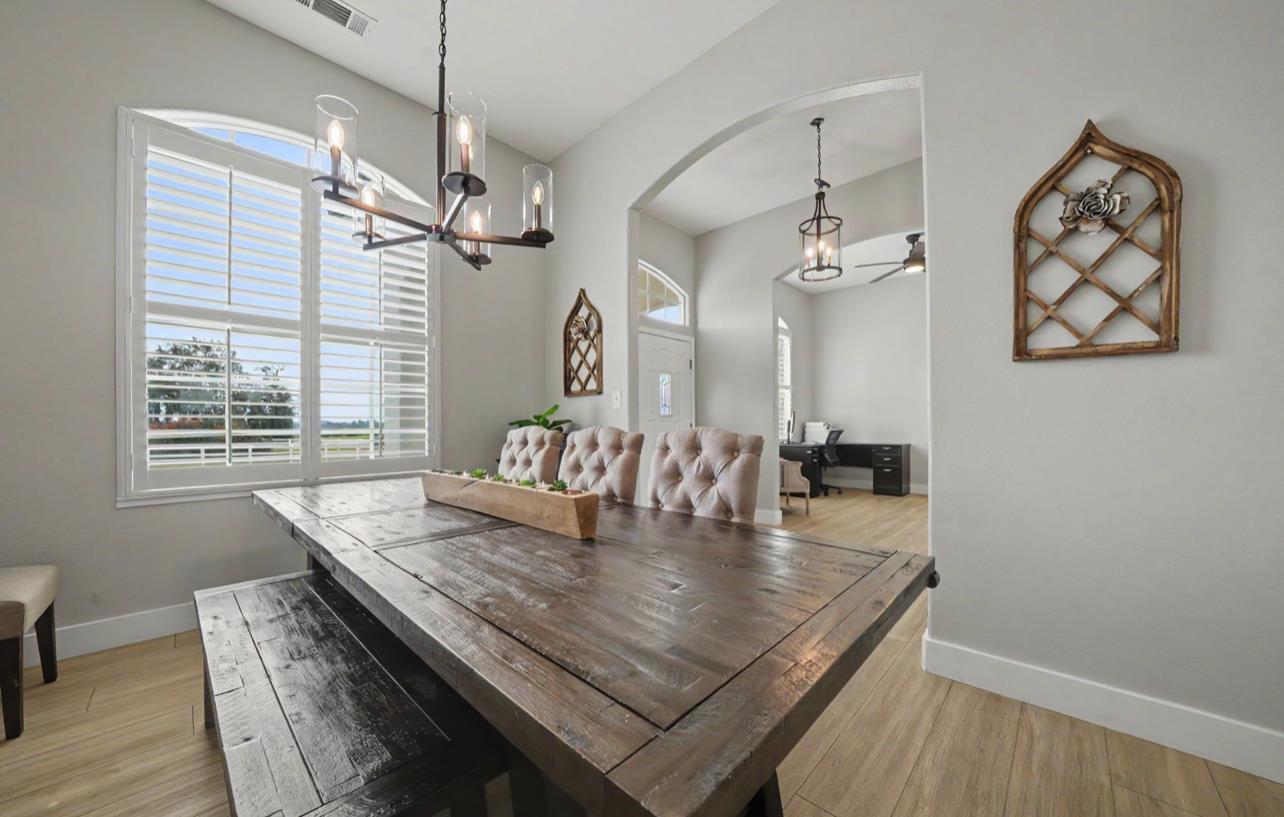 5600 Ferseyna Way Valley Springs, CA 95252 - Photo 46 of 94 a dining room with wooden floor a chandelier a wooden table and chairs