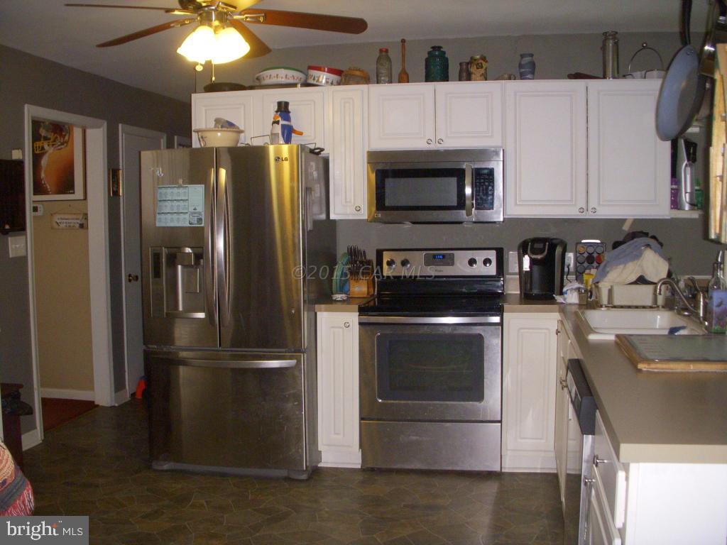 7674 Bethel Road Willards, MD 21874 - Photo 2 of 11 a kitchen with stainless steel appliances granite countertop a refrigerator a stove a sink and a microwave