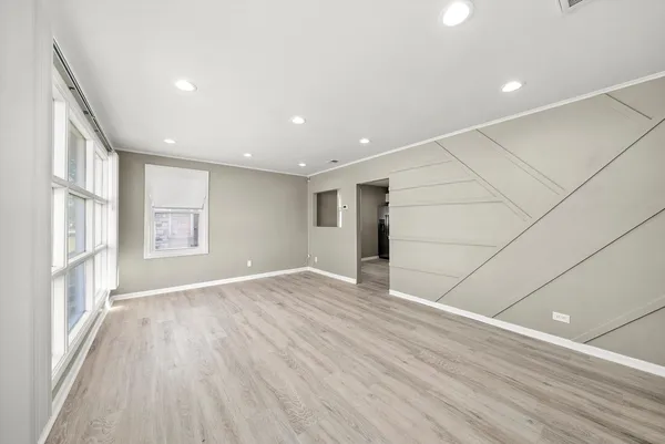 a view of an empty room with a window and wooden floor