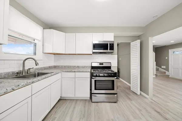 a kitchen with stainless steel appliances granite countertop a stove a sink and a microwave