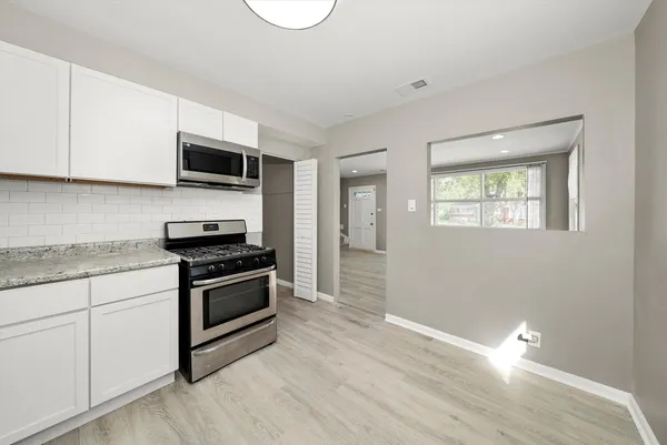 a kitchen with stainless steel appliances granite countertop a stove a sink and a microwave