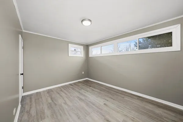a view of an empty room with wooden floor and closet
