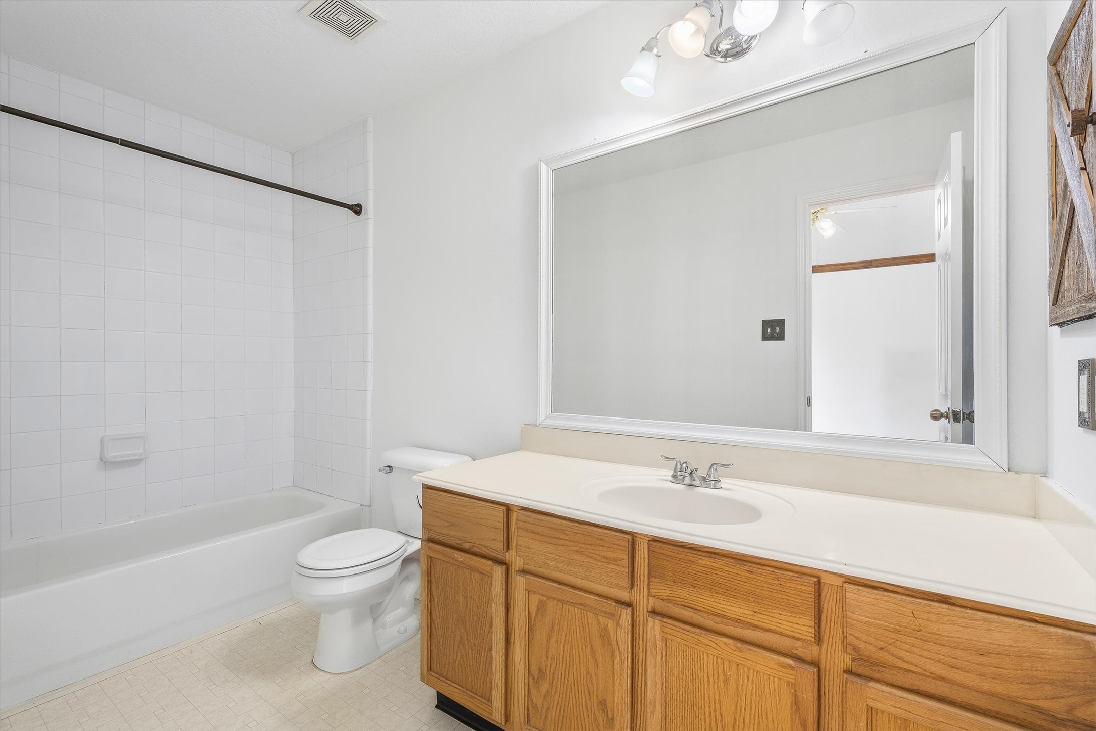 5426 Bourgeois Road Houston, TX 77066 - Photo 27 of 43 Bright primary bathroom featuring a large mirror, wooden vanity with ample storage, and a clean white tile bathtub.
