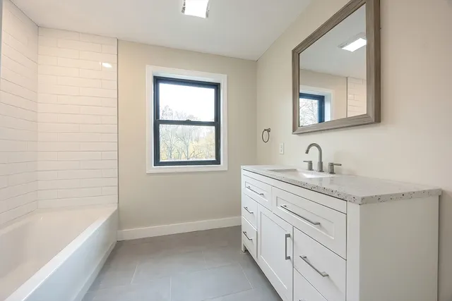 a bathroom with a granite countertop sink a mirror and a bathtub