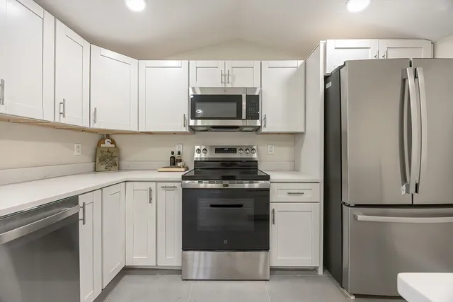 a kitchen with white cabinets and stainless steel appliances