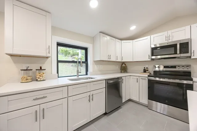 a kitchen with granite countertop white cabinets sink and stainless steel appliances