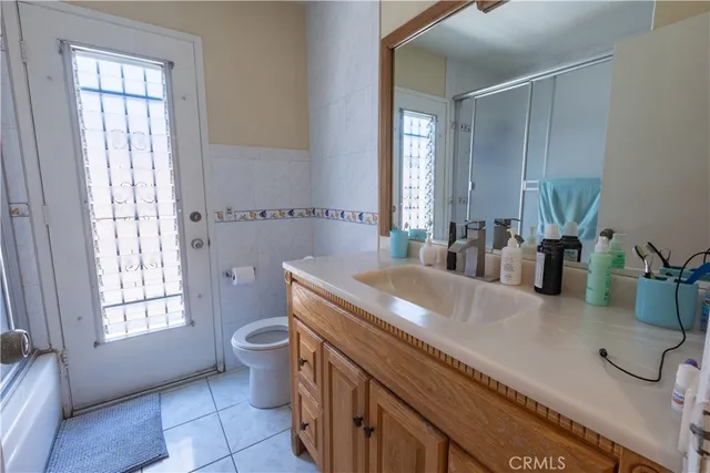 a bathroom with a granite countertop sink a toilet a mirror and window