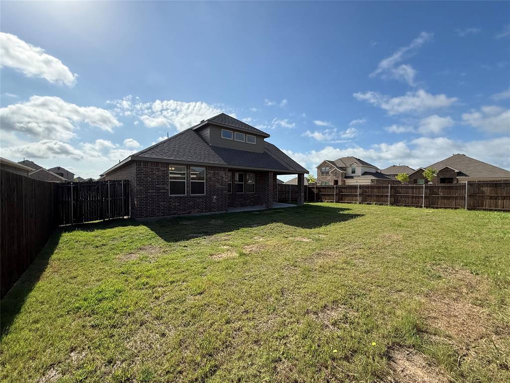 1306 Colonial Bluff Lane Princeton, TX 75407 - Photo 25 of 27 Expansive backyard featuring a full privacy fence, a covered patio, and a dormer window with multiple panes