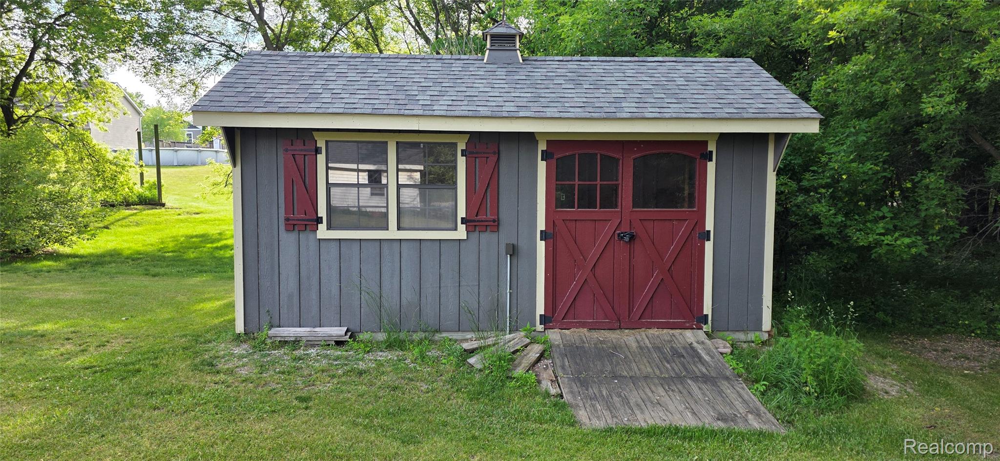 14062 Sanford Road Addison, MI 49220 - Photo 57 of 61 Outdoor storage shed with board and batten siding, red barn doors, exterior windows with red shutters, and a shingled roof