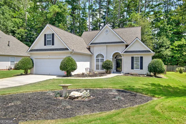 a view of a white house next to a yard and a large tree
