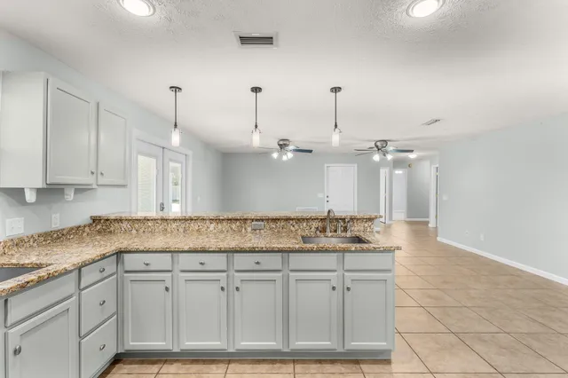 a view of an empty room and chandelier fan