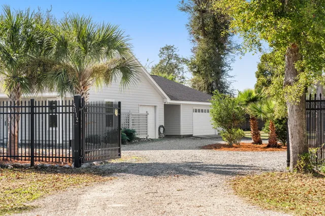 a view of a white house with a small yard and large trees