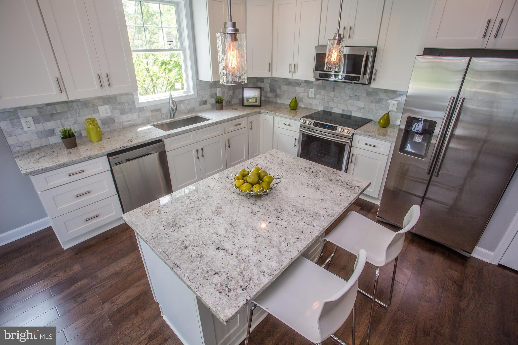 a kitchen with stainless steel appliances granite countertop a sink dishwasher stove refrigerator and microwave with wooden floor