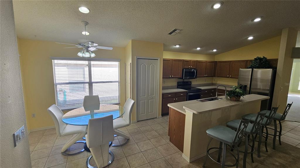 371 Quane Avenue Spring Hill, FL 34609 - Photo 24 of 45 a kitchen with a table chairs refrigerator and cabinets