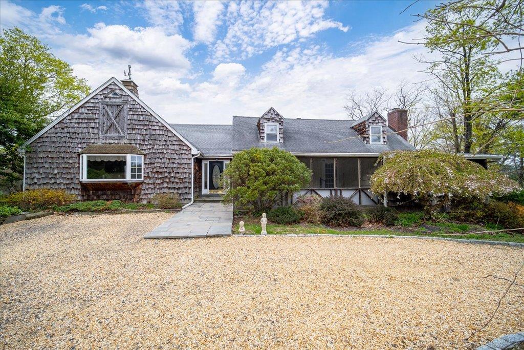 Cape cod-style house featuring roof with shingles and a chimney
