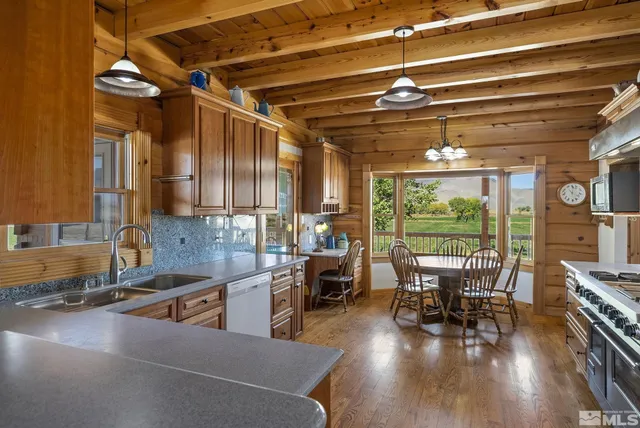 a kitchen with stainless steel appliances granite countertop a table chairs and a wooden floor