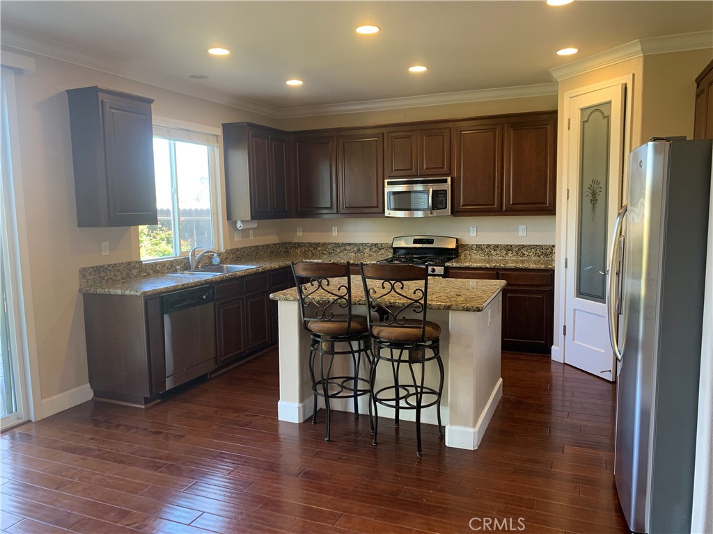 538 Burnt Ranch Way Chico, CA 95973 - Photo 7 of 34 a kitchen with stainless steel appliances wooden floors and white cabinets