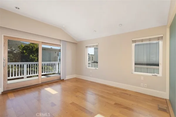 a view of a big room with wooden floor and windows
