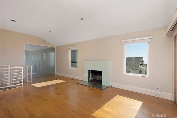 an empty room with windows and fireplace