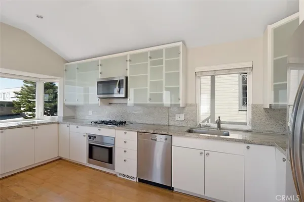a kitchen with granite countertop white cabinets sink and stainless steel appliances