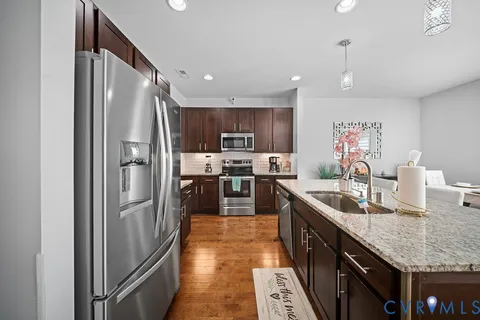 a kitchen with stainless steel appliances granite countertop a sink refrigerator and cabinets