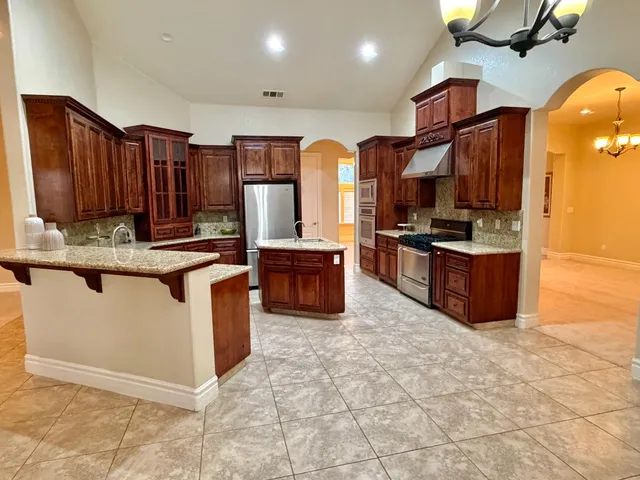 a kitchen with stainless steel appliances granite countertop a stove a sink and a microwave