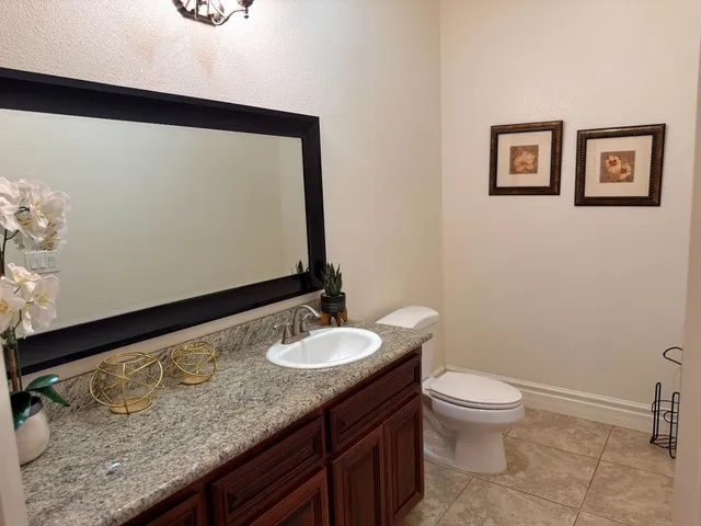 a bathroom with a granite countertop sink toilet and mirror