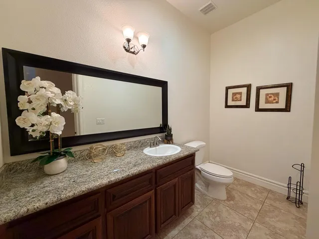 a bathroom with a granite countertop sink a toilet and mirror