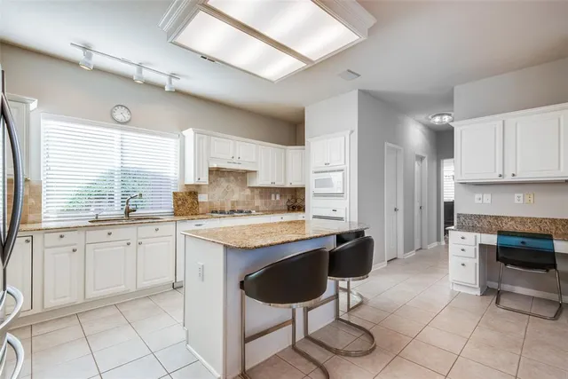 a kitchen with stainless steel appliances granite countertop a stove a sink dishwasher and a refrigerator with white cabinets