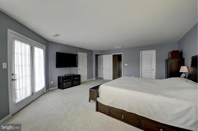 a spacious bedroom with a bed and a flat screen television