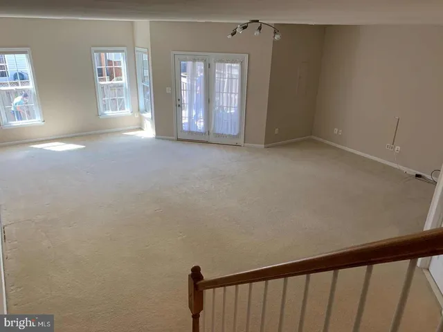 a view of an empty room with window and chandelier fan