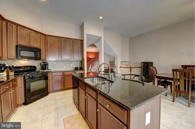 a kitchen with stainless steel appliances granite countertop a sink a stove top oven a counter space and cabinets